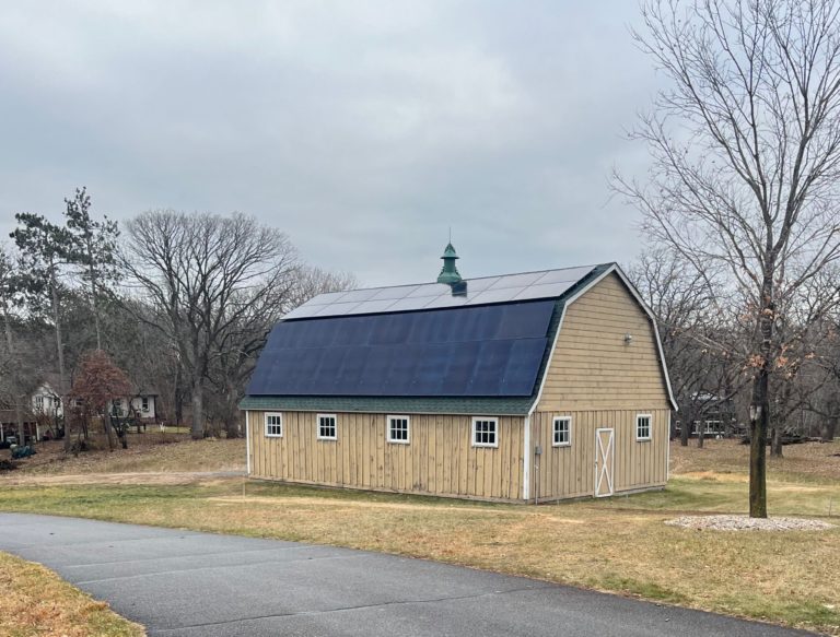 Installation of a solar array on a yellow barn with a gambrel roof in Afton, Minnesota.